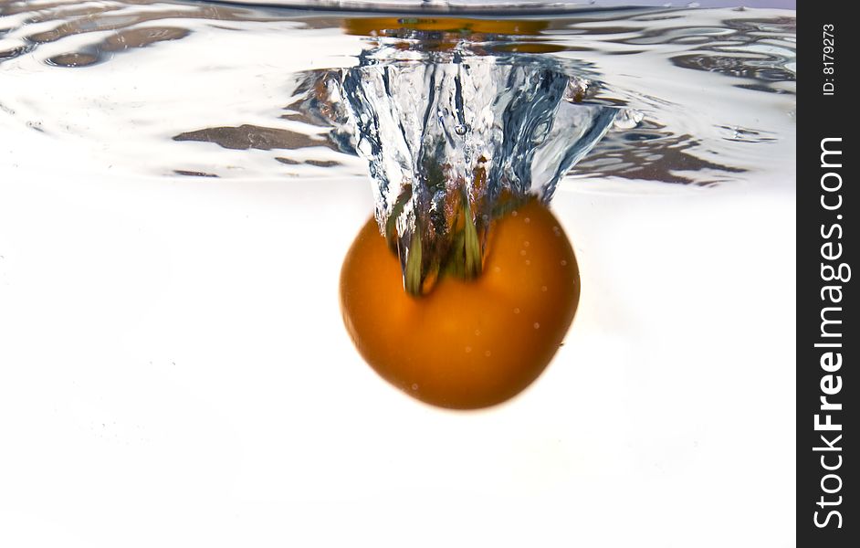 Tomato dropped into water with water splash