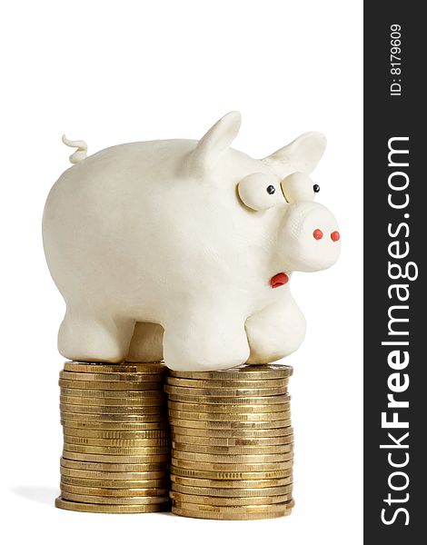 Plasticine piggy bank stands on heaps of gold coins