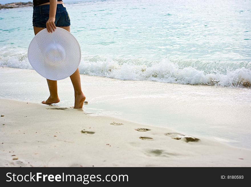 Lady standing on the beach with white hat in hands. Lady standing on the beach with white hat in hands