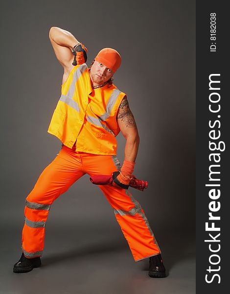 The worker in orange clothes on a grey background in studio. The worker in orange clothes on a grey background in studio