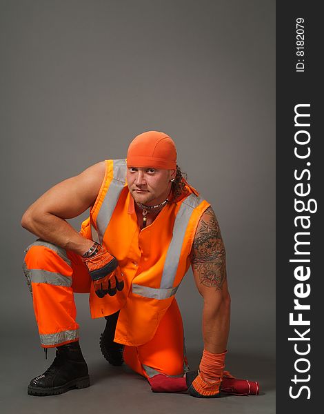 The worker in orange clothes on a grey background in studio. The worker in orange clothes on a grey background in studio