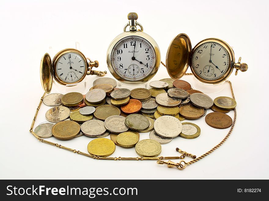 An antique pocket watch with gold fob surrounded by coins of the world. An antique pocket watch with gold fob surrounded by coins of the world