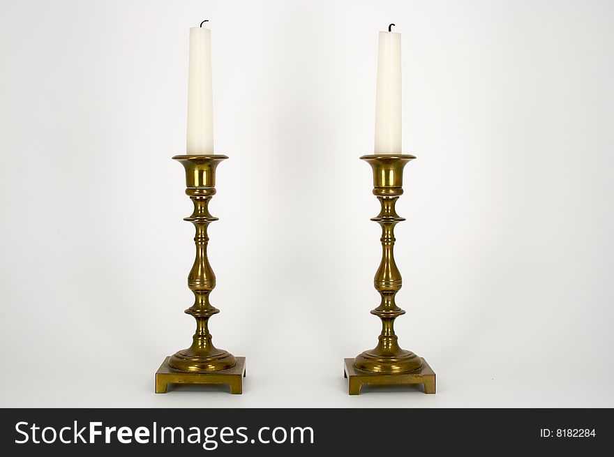 Two Brass Candelabras with white candles with burned wicks.  The candelabras are a simple classic design