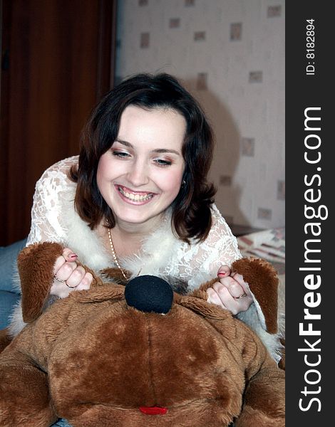 The girl cheerfully laughs, playing with a plush dog. The girl cheerfully laughs, playing with a plush dog