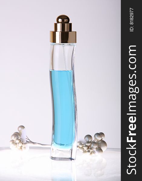 Tall perfume bottle with blue liquid in studio lighting