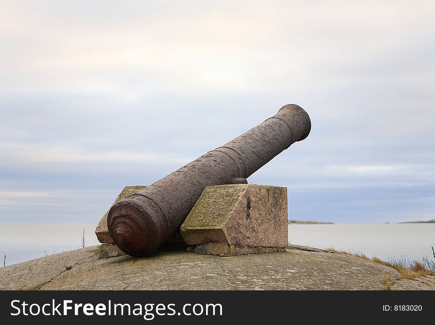 An old rusty iron cannon on Finnish coast aimed at sea.
