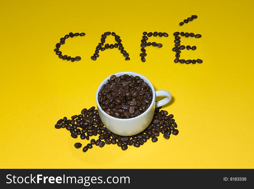 Cafï¿½ written with beans on yellow background.