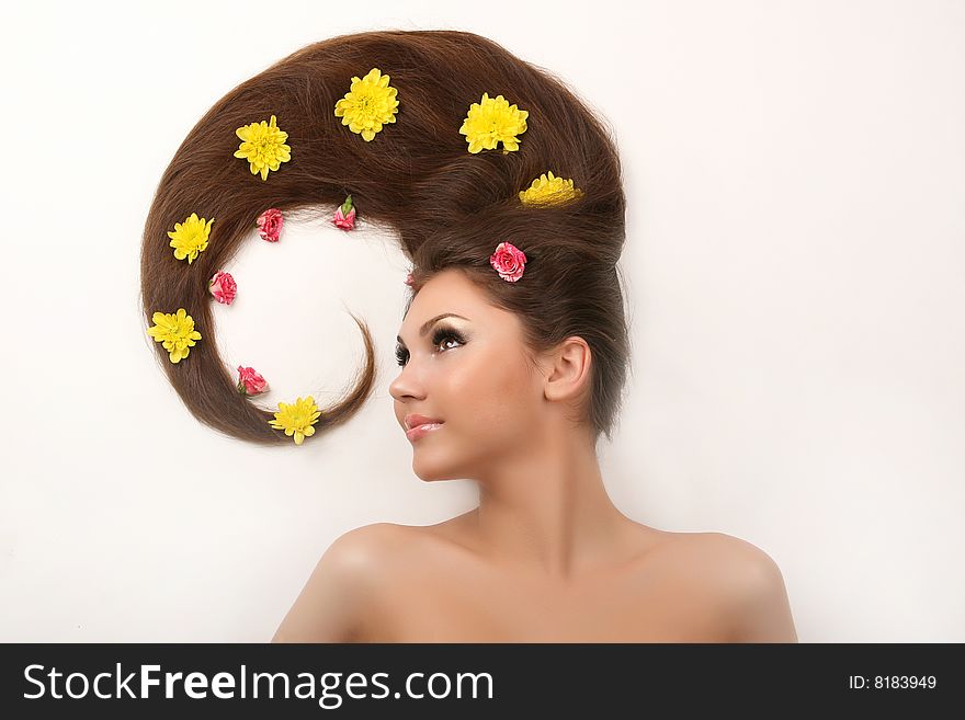 Attractive young woman with flowing hair and flowers on white background