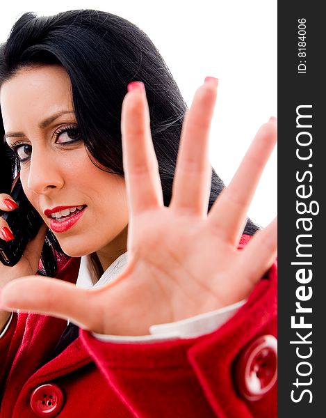 Young woman talking on phone and showing stopping gesture on an isolated  white background