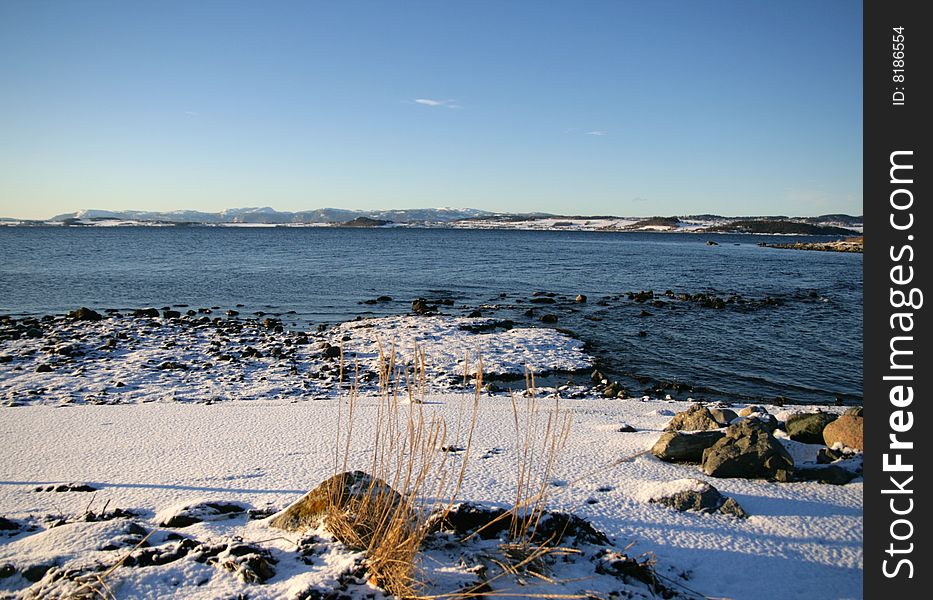 Snow on the shore by a Norwegian fjord. Snow on the shore by a Norwegian fjord