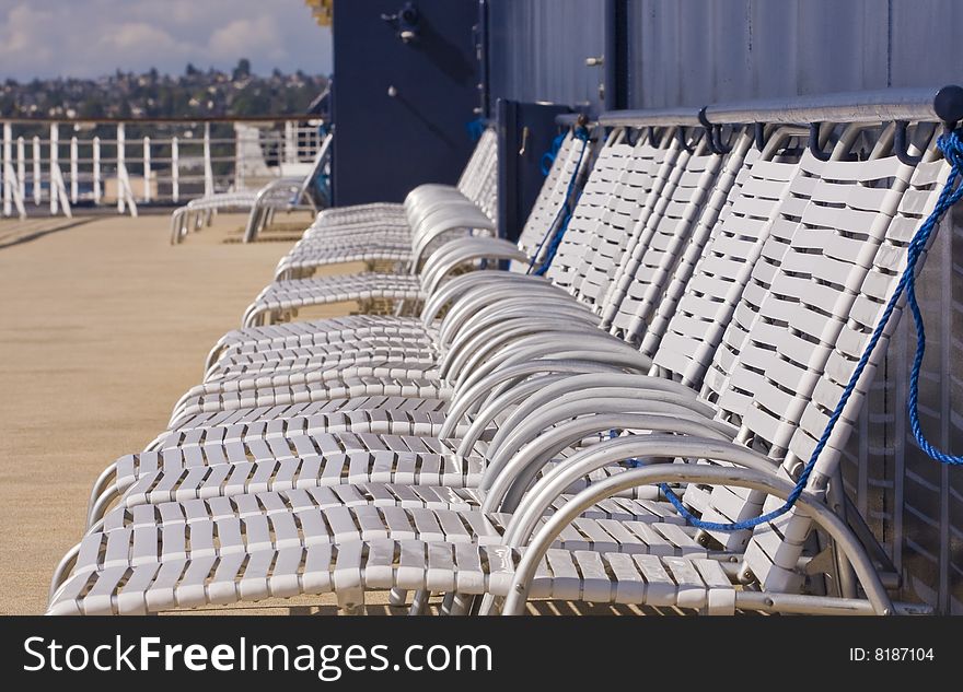 White vinyl chaise lounges lined up on the deck of a cruise ship. White vinyl chaise lounges lined up on the deck of a cruise ship