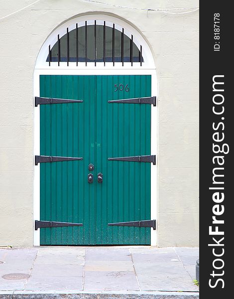 Arched doorway with green doors and antique hinges, in vertical orientation