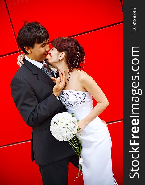 Funny bride and groom by the red wall