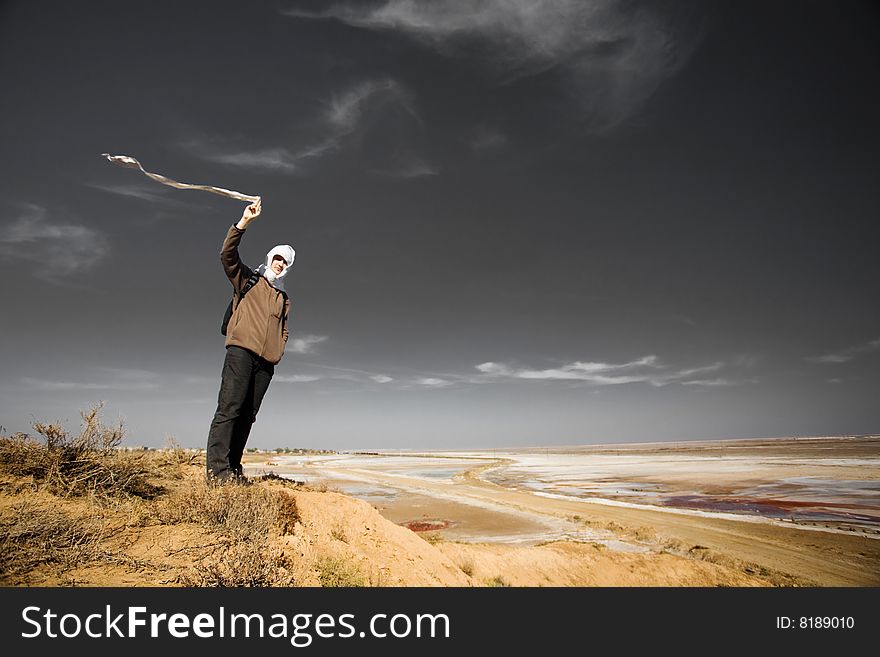 Man with a white cloth on the bank of a dry lake