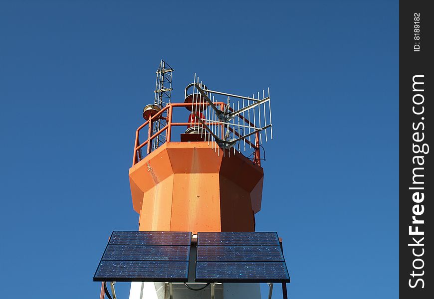 A lighthouse is equipped with solar power panels on a clear blue sky day. A lighthouse is equipped with solar power panels on a clear blue sky day.