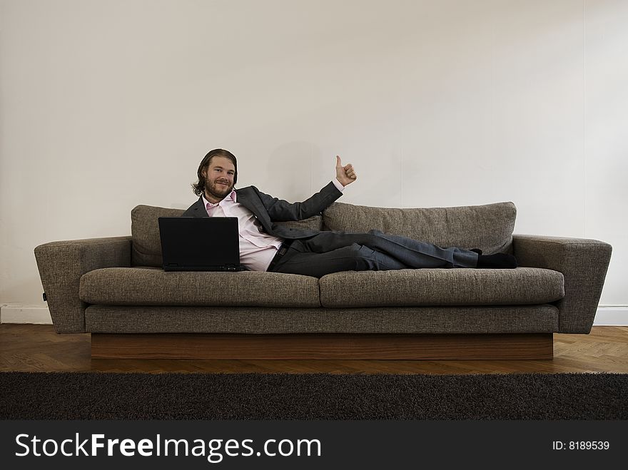 Businessman lies on the sofa and doin thumbs up