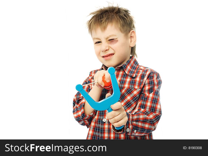 Little boy with a bruise and one eye closed aiming at us with a slingshot. Little boy with a bruise and one eye closed aiming at us with a slingshot