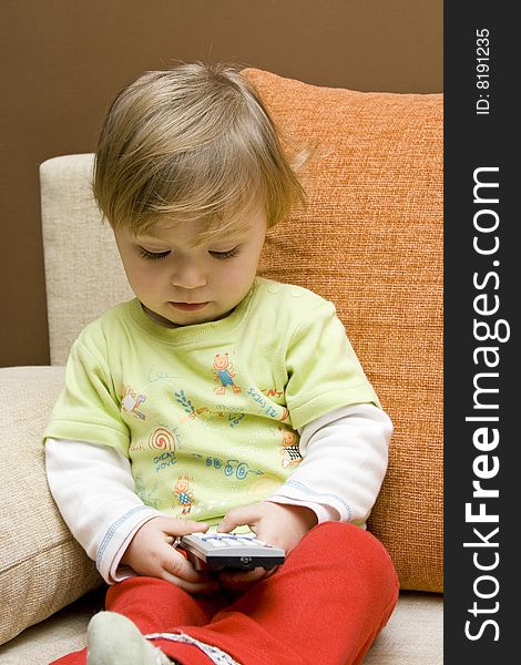 Sweet baby girl with remote control on sofa