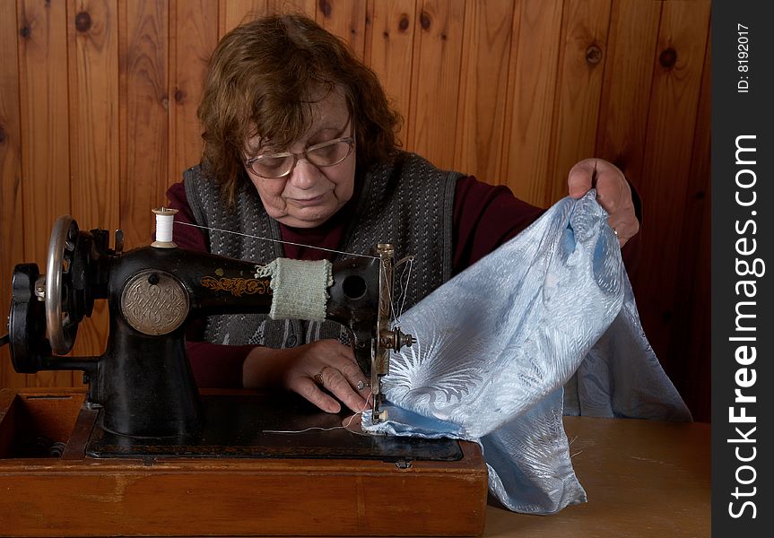 The old woman sews on the sewing machine
