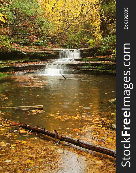 A small stream cascades in a wooded canyon in autumn. A small stream cascades in a wooded canyon in autumn