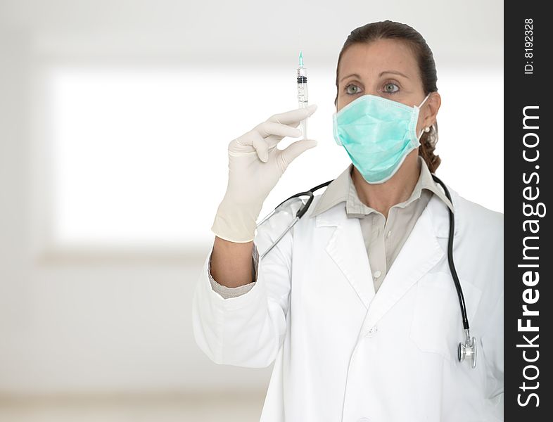 Female doctor holding a syringe on hospital blured background