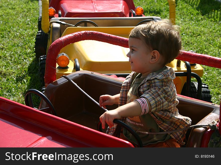 A toddler driving a car at an amusement park. A toddler driving a car at an amusement park.