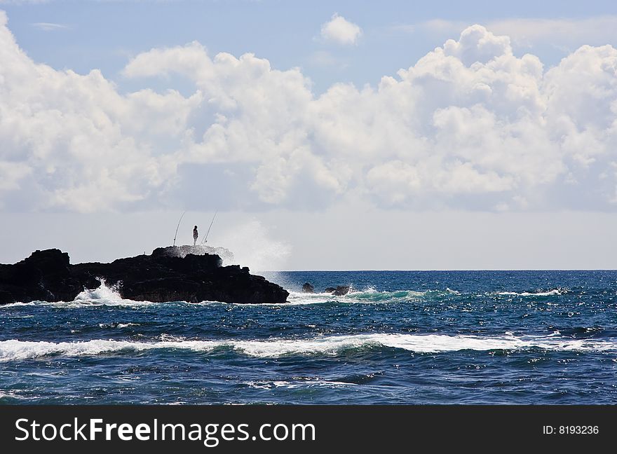 Silhouette of a fisherman on rocky headland