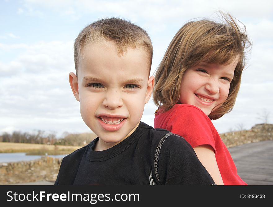 Two Children Smile for the Camera at the Park.
