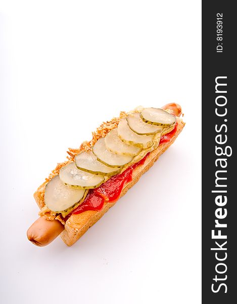 Hotdog with onion and cucumber on the white surface. Hotdog with onion and cucumber on the white surface