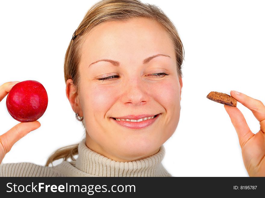 Young blonde female holding a fruit in one hand and a tempting cake in the other (isolated on white). Young blonde female holding a fruit in one hand and a tempting cake in the other (isolated on white)