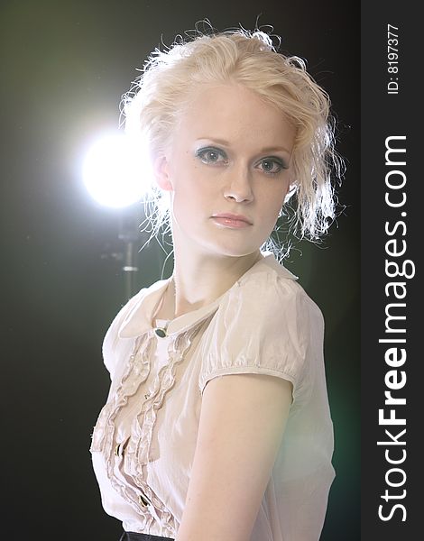 Beautiful blond fashion model posing in studio with backlights. Beautiful blond fashion model posing in studio with backlights