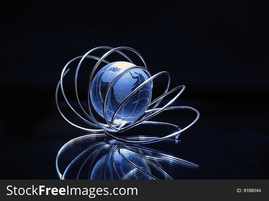 Glassy globe inside tangle made from wire on dark background. Glassy globe inside tangle made from wire on dark background