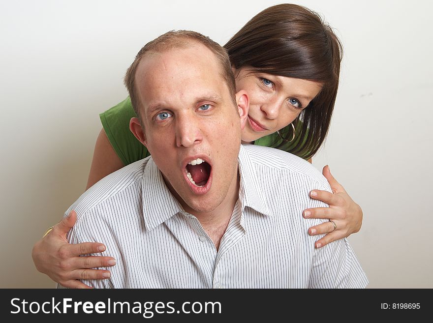 A young couple in love. The woman hugs the man from behind. The man is yawning. A young couple in love. The woman hugs the man from behind. The man is yawning.