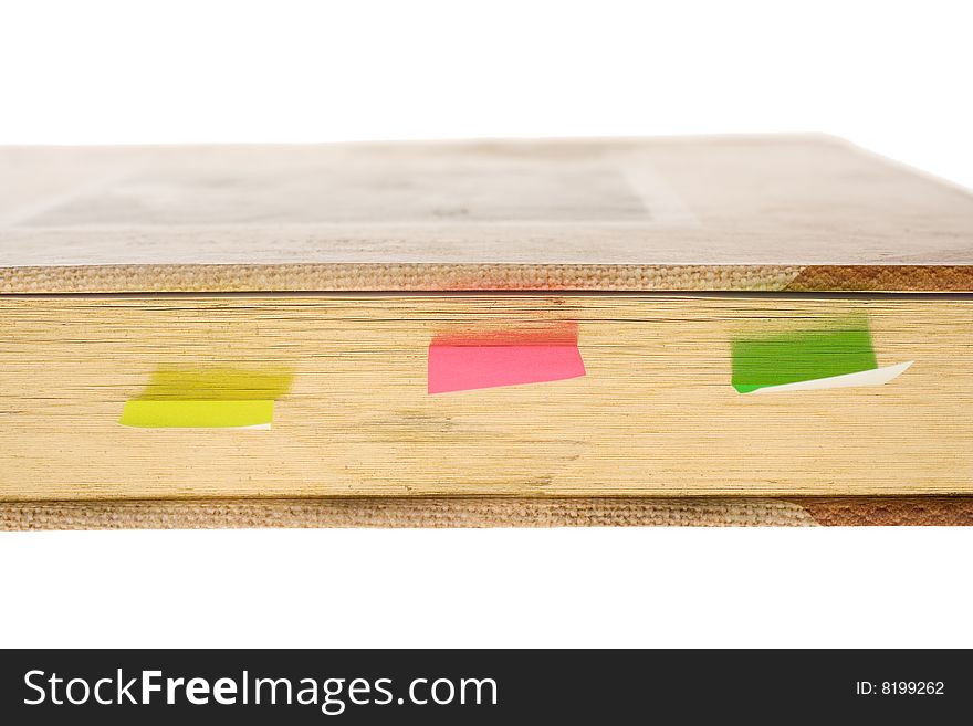 Detail of book with gold leaves and note pads on white background