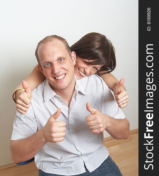 A young couple in love shows a thumbs up sign in their new appartment. A young couple in love shows a thumbs up sign in their new appartment.