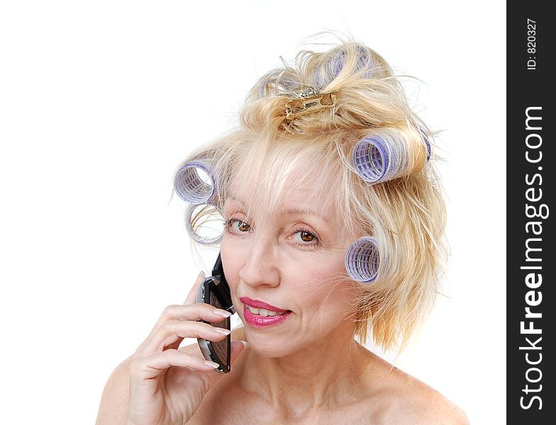 A blonde woman with lavender curlers in her hair is talking on her cell phone. A blonde woman with lavender curlers in her hair is talking on her cell phone.