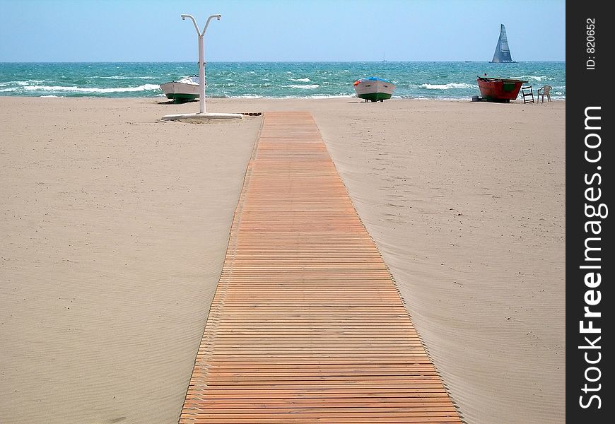 Wooden footbridge in the sand of a beach for access to the sea. Wooden footbridge in the sand of a beach for access to the sea