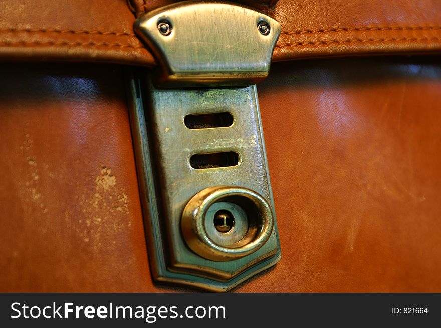 Brassy clasp on brown briefcase. Brassy clasp on brown briefcase