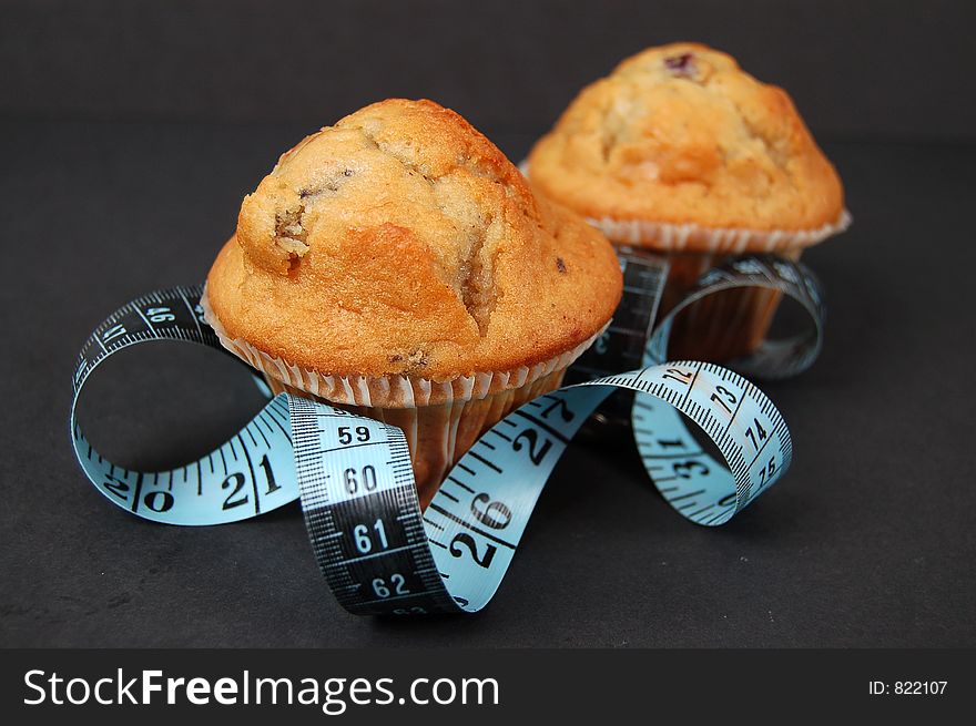 This is an image of blueberry muffins and a measuring tape. This is a metaphor for dieting. This is an image of blueberry muffins and a measuring tape. This is a metaphor for dieting.