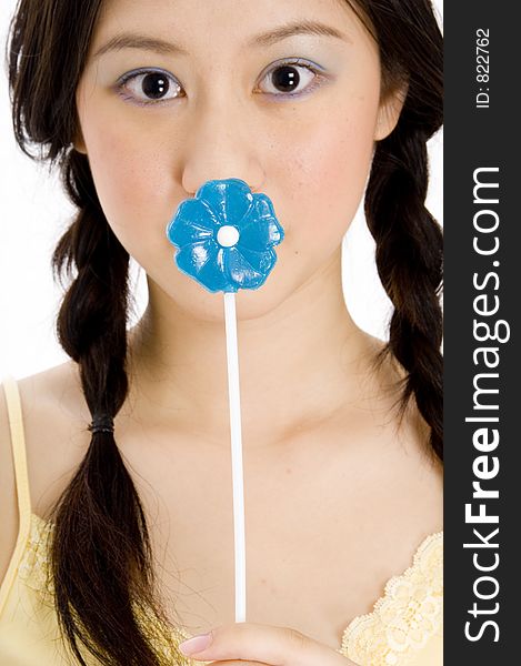 A young woman covers her mouth with a blue lollipop. A young woman covers her mouth with a blue lollipop