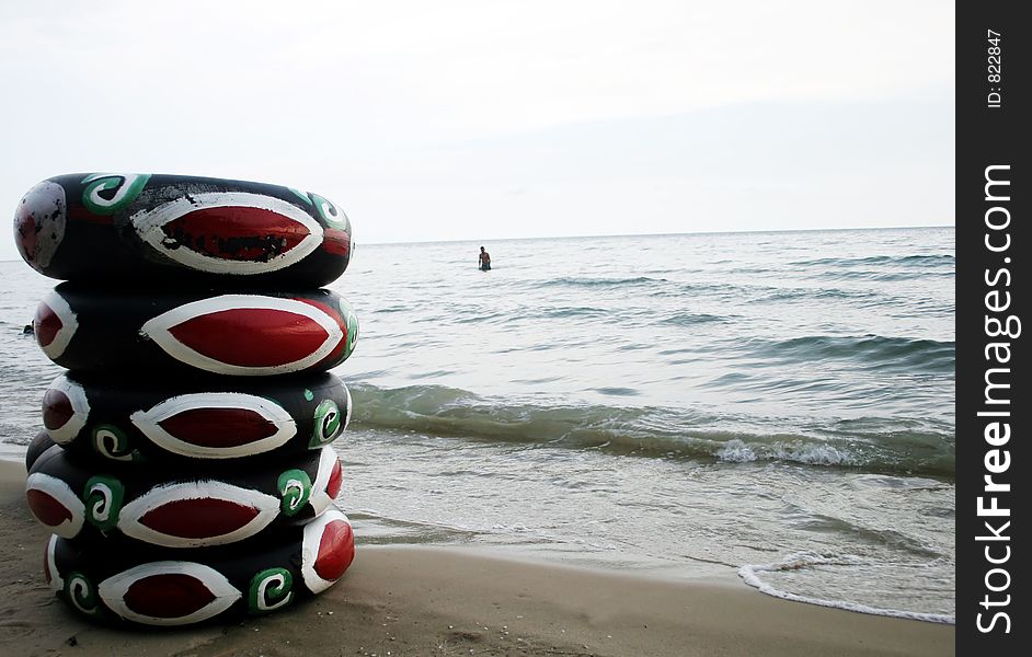 Beach tubes on the sand with a man swimming in the background - copy space. Beach tubes on the sand with a man swimming in the background - copy space