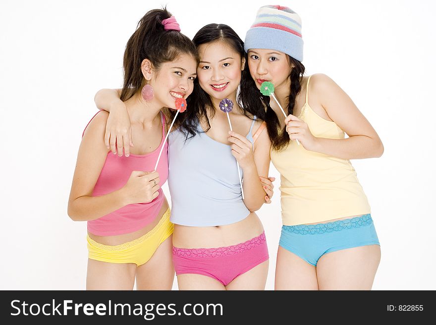 Three asian teenagers in colorful clothes with lollipops. Three asian teenagers in colorful clothes with lollipops