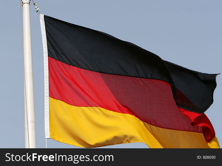 The german flag flying from a flagpole. The german flag flying from a flagpole