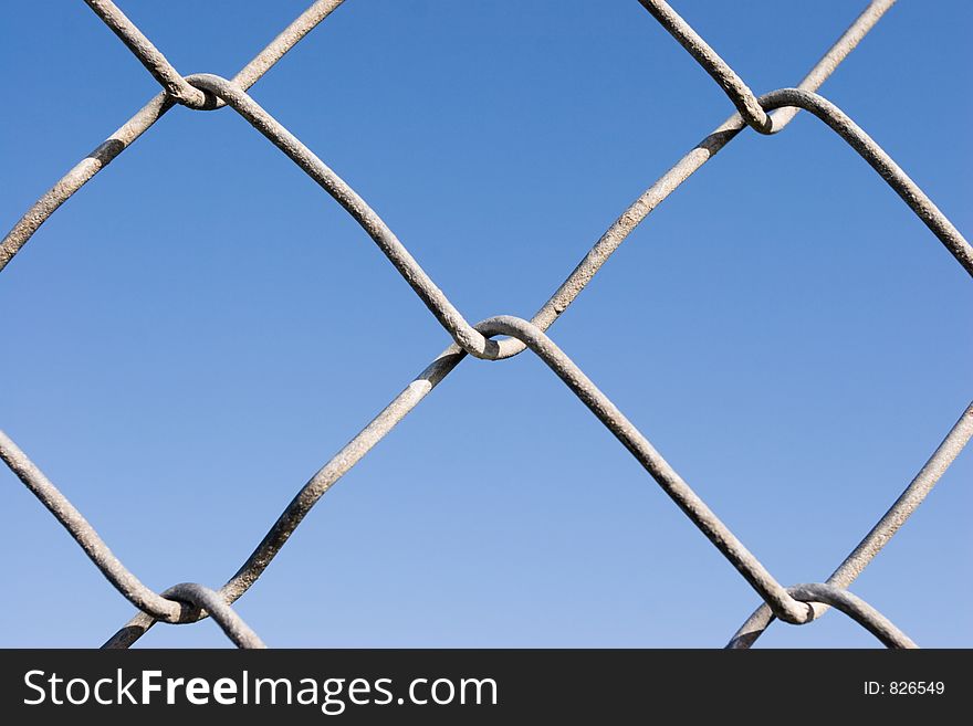 Closeup of a chin link fence with blue sky in the background. Closeup of a chin link fence with blue sky in the background