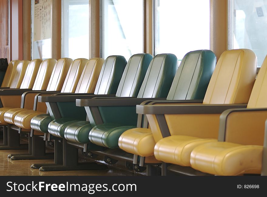 A row of vacant padded arm chairs to comfort passengers during their long wait to begin boarding. A row of vacant padded arm chairs to comfort passengers during their long wait to begin boarding.