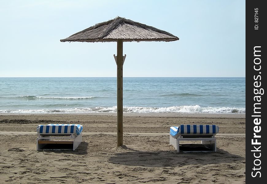 Two chairs under an umbrella in the beach. Two chairs under an umbrella in the beach