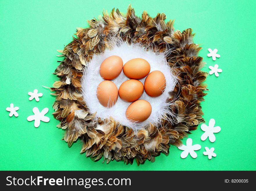 HennÂ´s egg in a nest on green background. HennÂ´s egg in a nest on green background