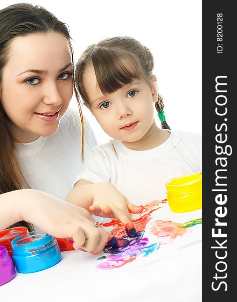 Young mother and her daughter sitting by the table and painting with finger paints. Young mother and her daughter sitting by the table and painting with finger paints