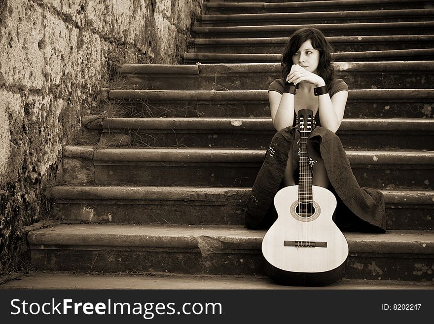 Young beautiful music performer caressing her guitar. Young beautiful music performer caressing her guitar