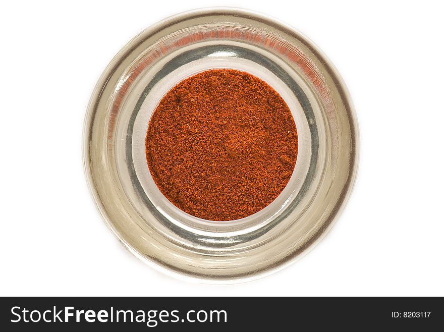 Red spice in glass container closeup isolated